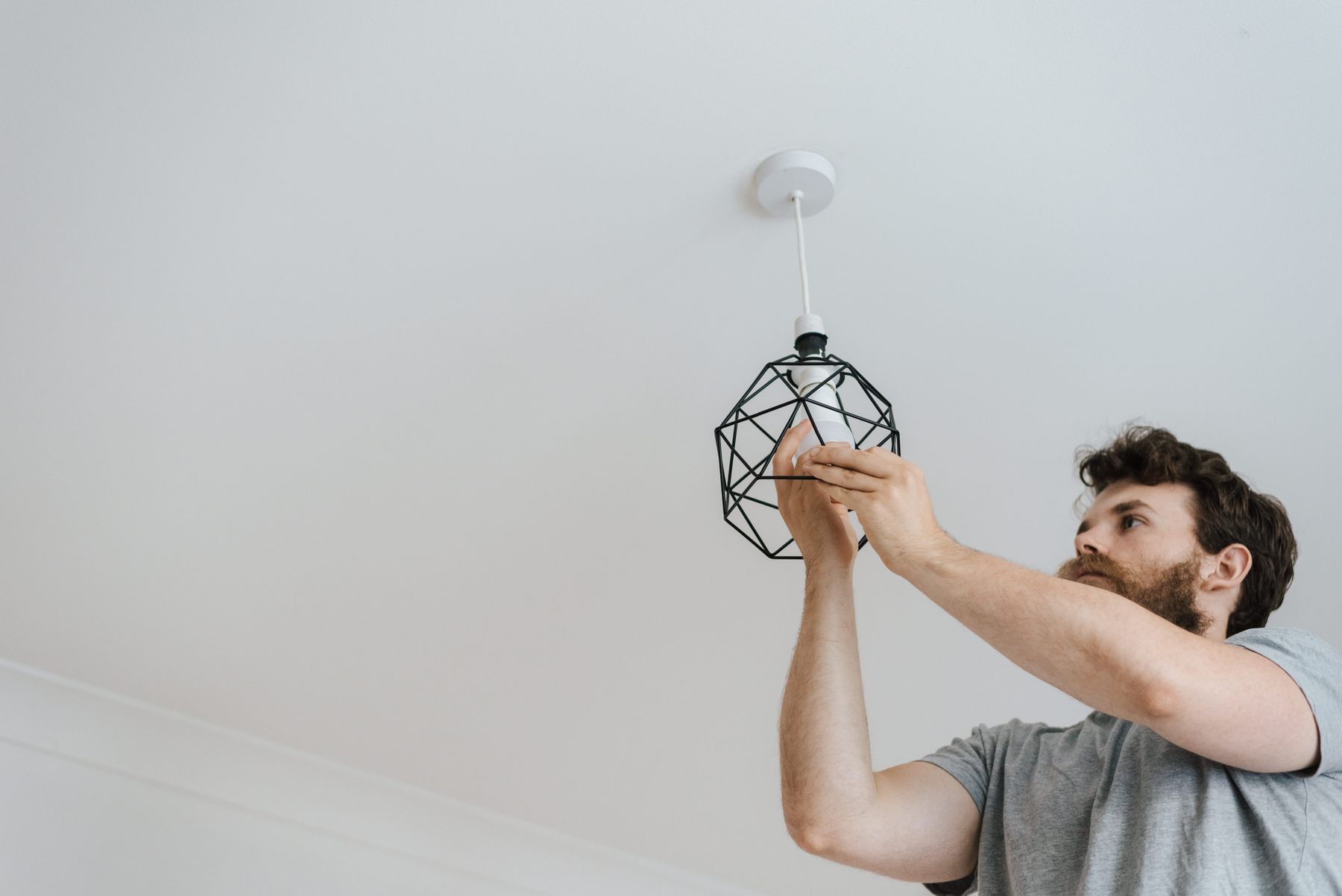 A tradesperson installing a ceiling light in a home